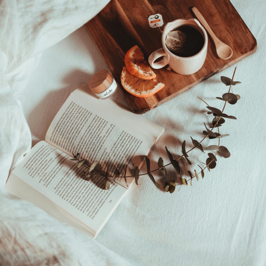 A serene scene of breakfast in bed featuring a book, coffee, and fresh fruit for a relaxing morning.