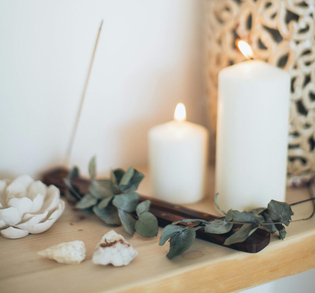 Calming still life featuring lit candles, eucalyptus, and shells for relaxation ambiance.